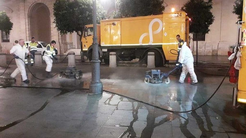 Operarios de Lipassam quitan la cera junto al Ayuntamiento de Sevilla.