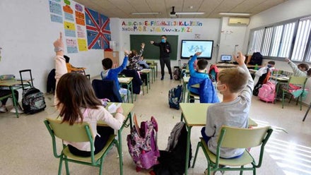 Niños y niñas sentados atendiendo al profesor.
