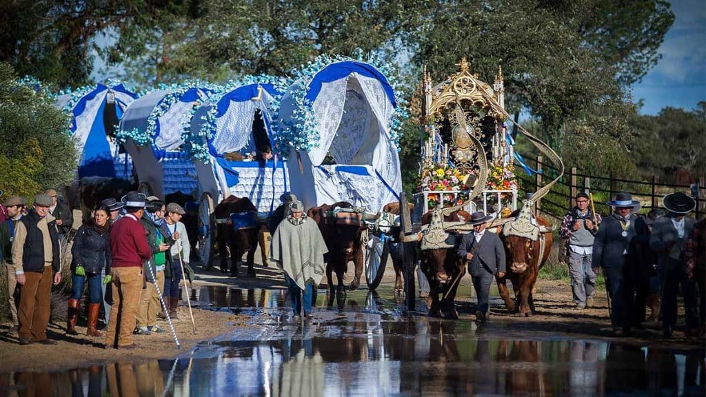 Carretas de colores cruzando el rio. Los romeros junto a ellas.