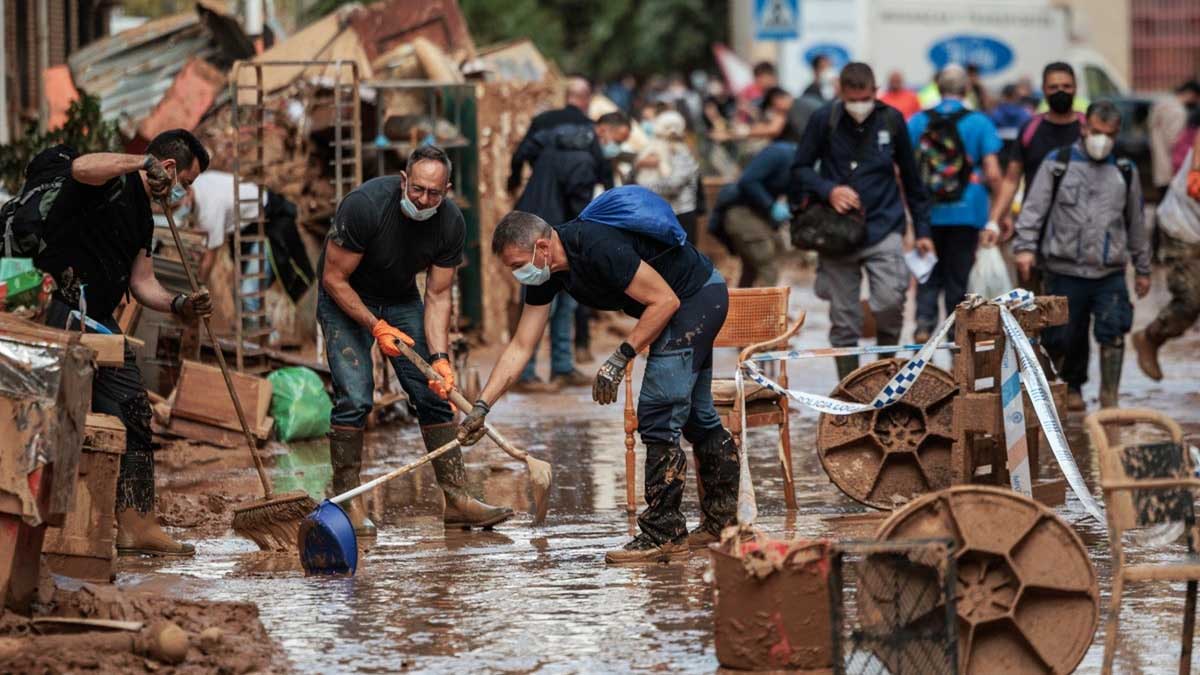 Personas limpiando el lodo y barro de las calles de Paiporta.