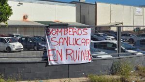 Vaya con una pancarta que dice "Bomberos Sanlúcar en ruinas" con letras rojas.
