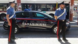 Carabinieri vestidos de uniforme con un coche tras de ellos con el cartel de "carabinieri", Policía.