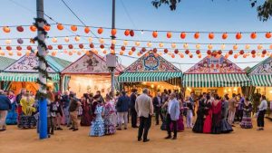 Casetas de Feria con personas en la calle charlando y bailando.