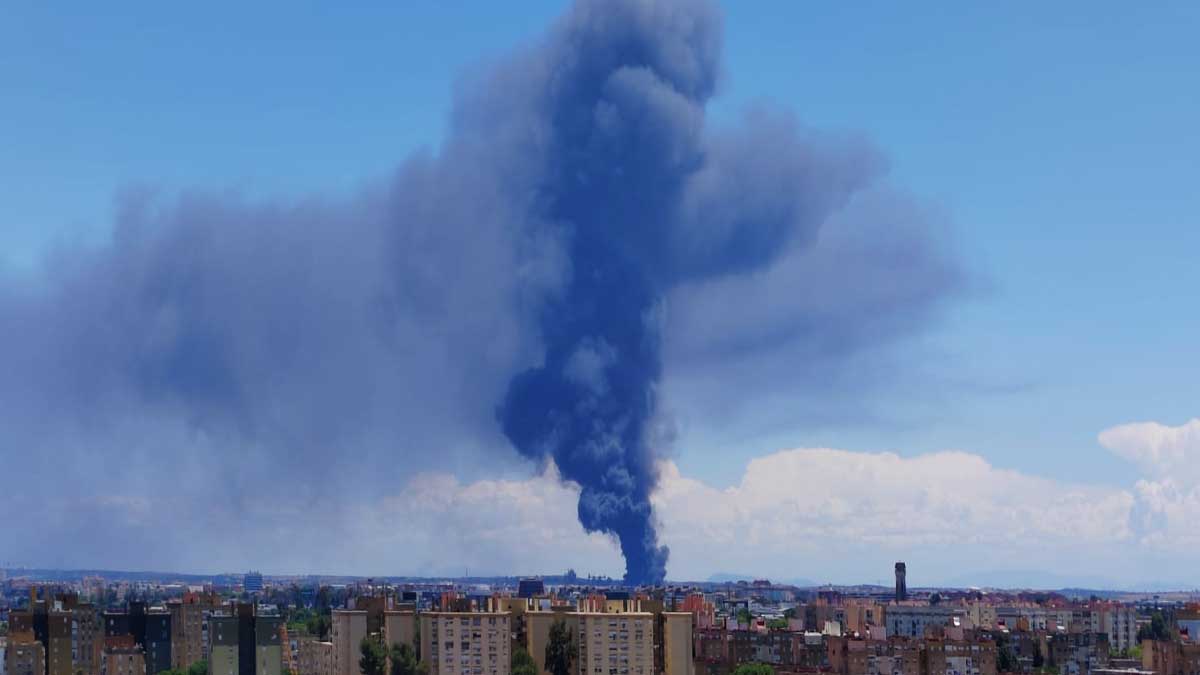 Gran columna de humo negro resaltando sobre el cielo azul de Sevilla.