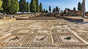 Bellos mosaicos de unas de las villas romanas de Itálicas, con árboles al fondo.