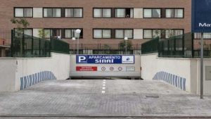 Entrada de acceso al parking con cartel en azul y blanco.