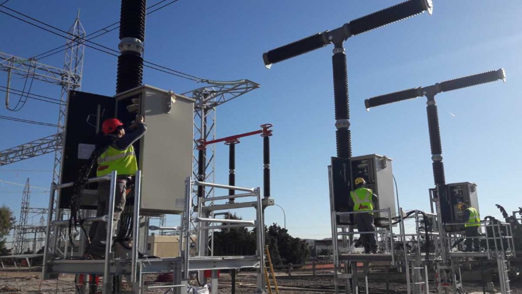 Dos operarios con chalecos reflectantes trabajando en la subestación eléctrica.