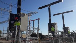 Dos operarios con chalecos reflectantes trabajando en la subestación eléctrica.