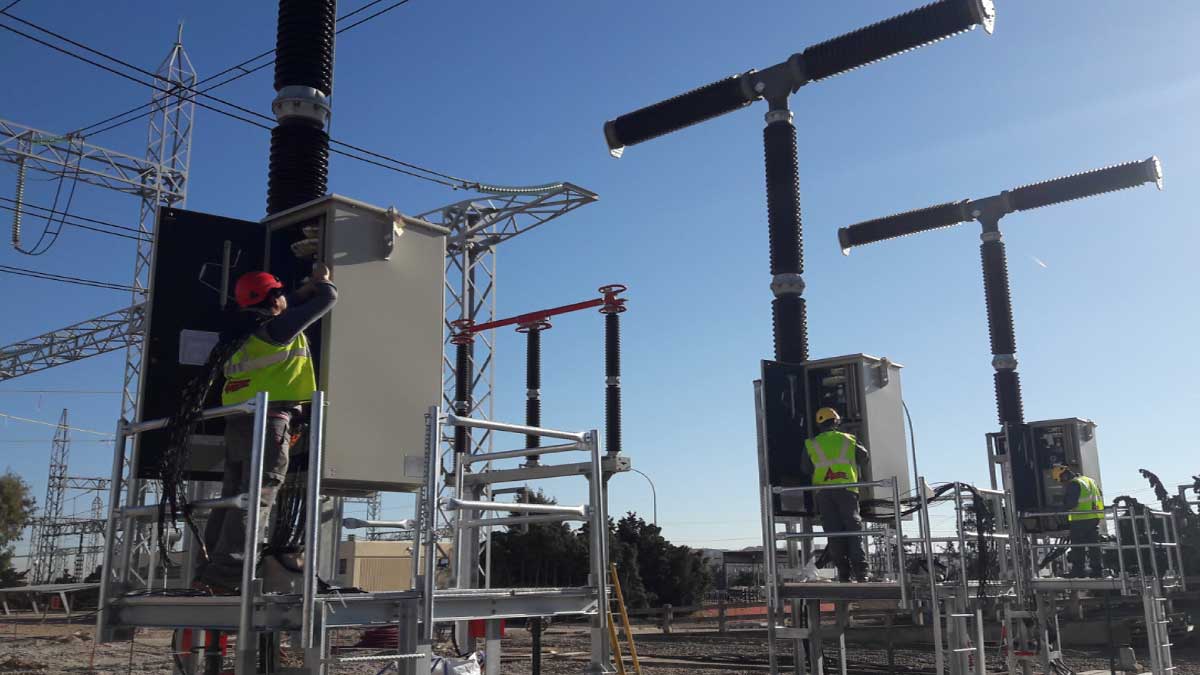 Dos operarios con chalecos reflectantes trabajando en la subestación eléctrica.