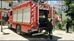 Camión rojo con bomberos en la parte trasera.