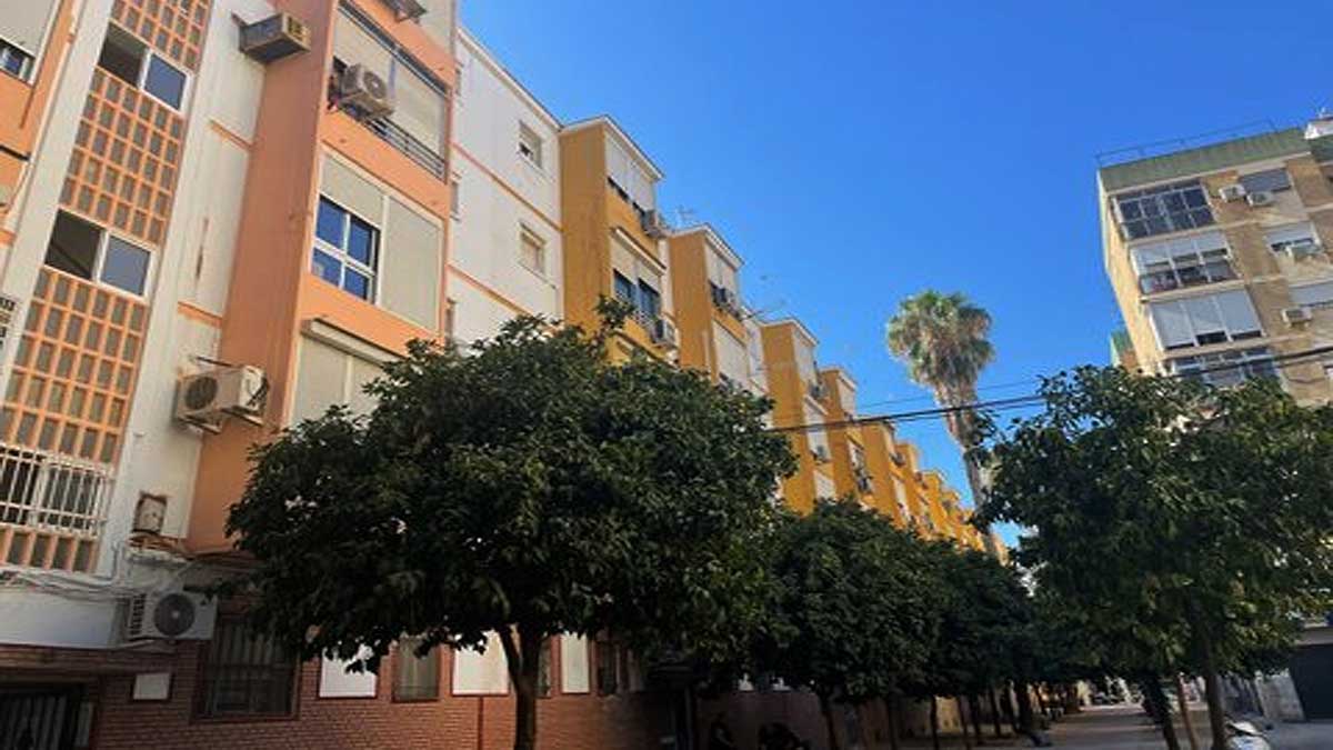 Edificio de viviendas en calle Constantina, en colores beige y anaranjado.