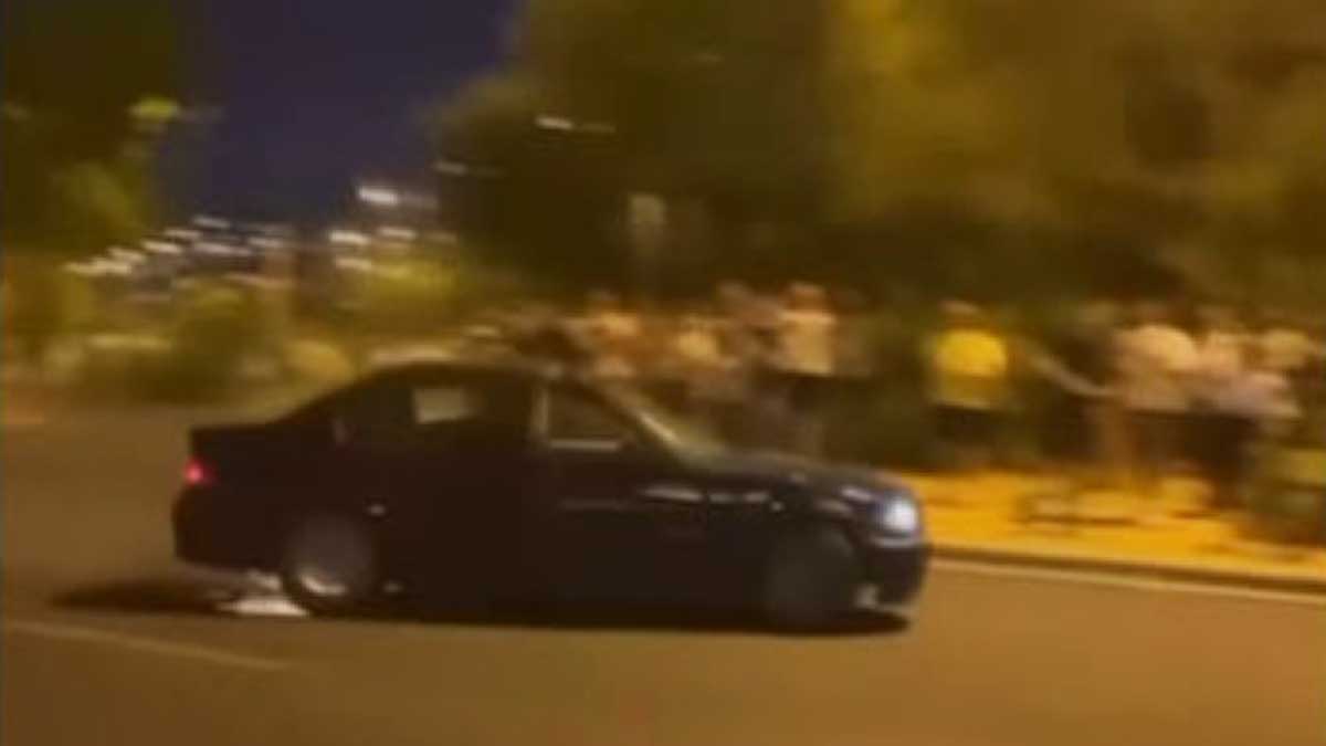 Público jaleando a un coche negro haciendo un derrape.