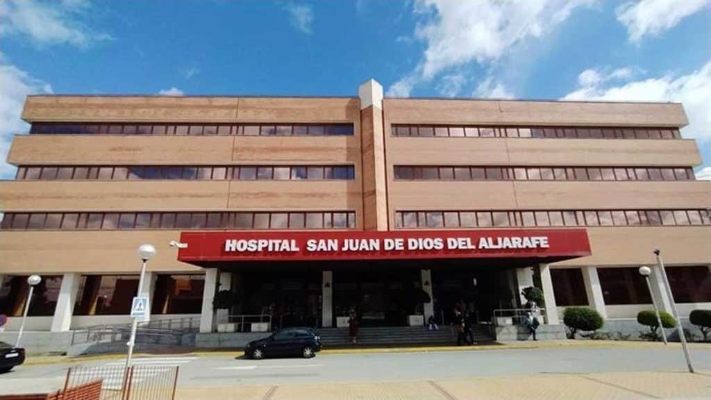 Edificio en ladrillo del hospital y letrero en rojo donde se lee Hospital de San Juan de Dios del Aljarafe.