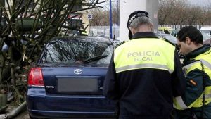Agente de la Policía Local y un Guardia Civil multando a un automóvil.