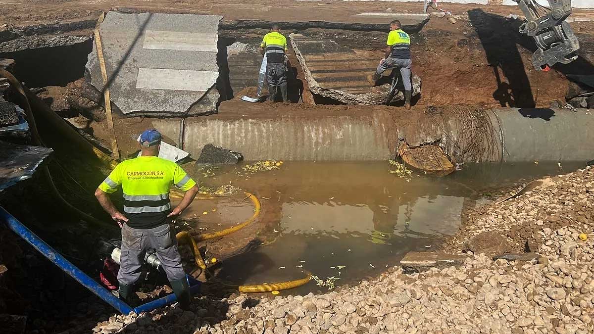 Enorme charco de agua provocado por la rotura de la tubería y operarios trabajando.