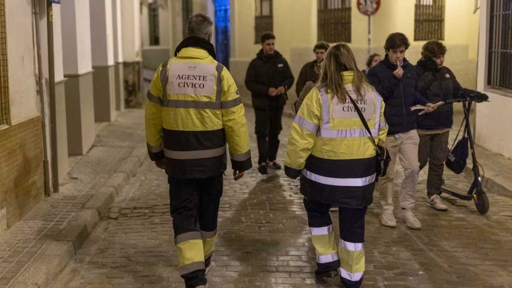 Dos serenos con uniforme amarillo fluorescente y azul patrullando por Sevilla.