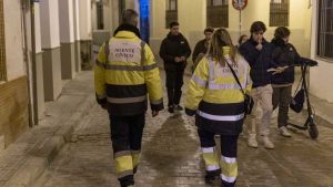 Dos serenos con uniforme amarillo fluorescente y azul patrullando por Sevilla.
