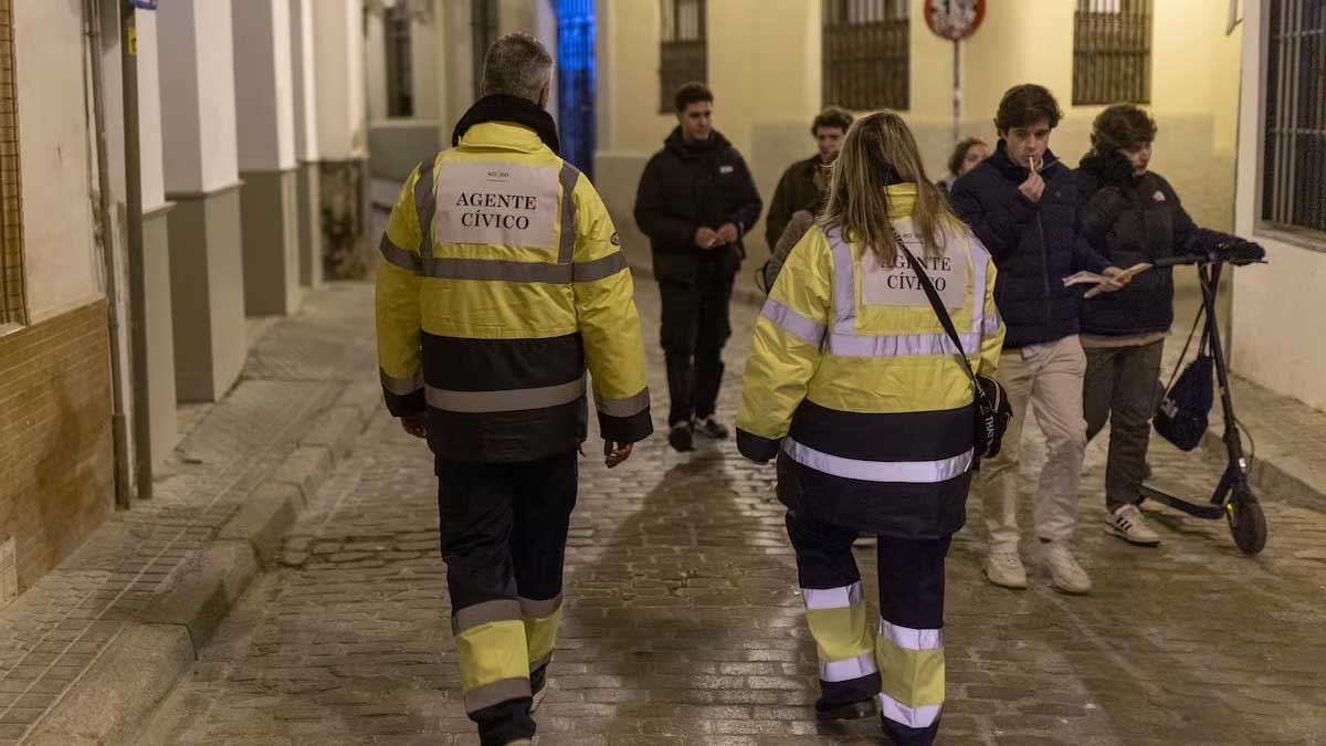 Dos serenos con uniforme amarillo fluorescente y azul patrullando por Sevilla.