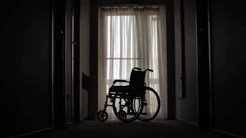 Silla de ruedas en el pasillo de una vivienda. En sombra.