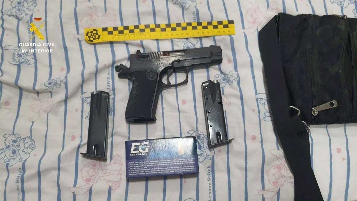 Arma y cargadores incautadas por la Guardia Civil sobre fondo blanco con rayas azules.