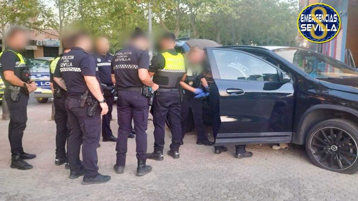 El vehículo del detenido, negro, junto a los policías locales de Sevilla.