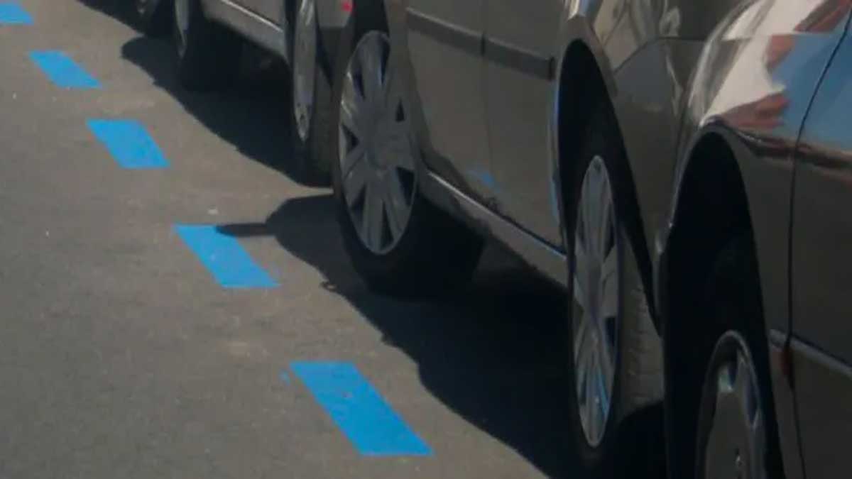Coches aparcados en zona azul, la carretera con las líneas de dicho color y las ruedas de los coches.