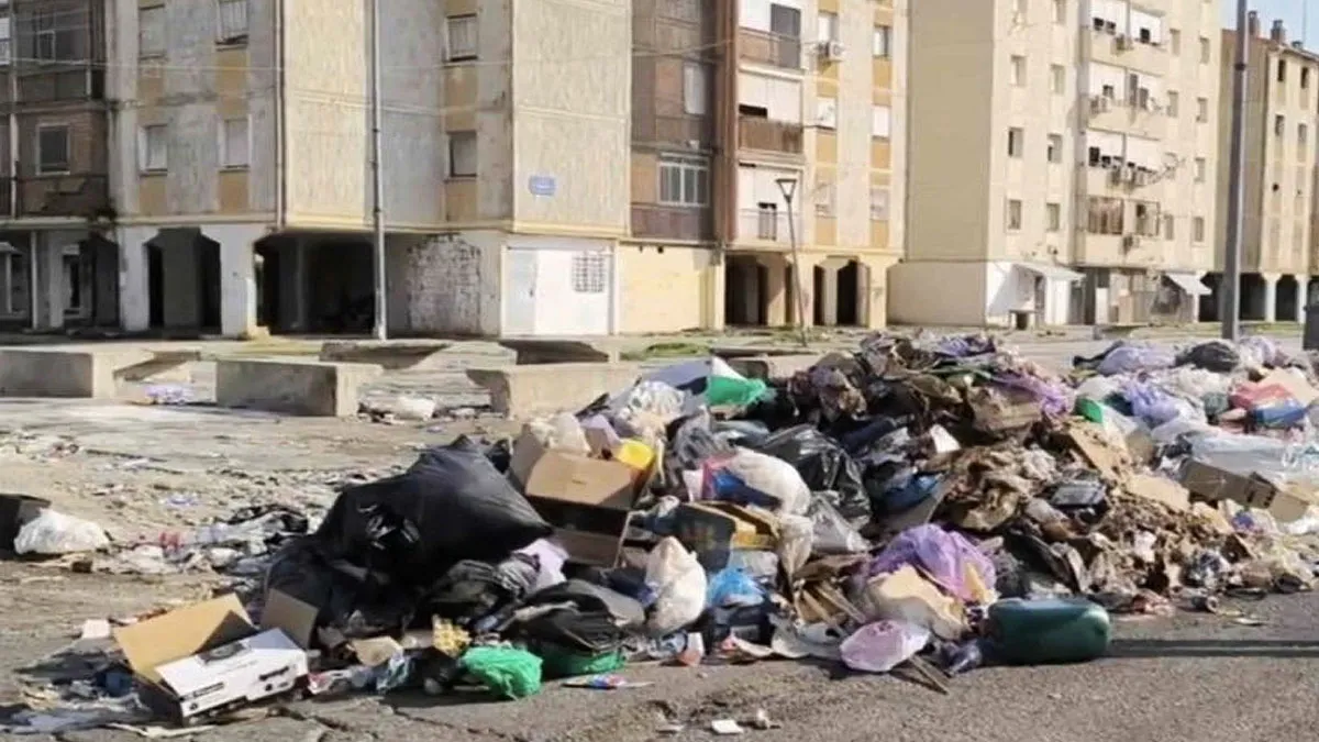 Montón de basura acumulado junto a unos edificios en el Polígono Sur.