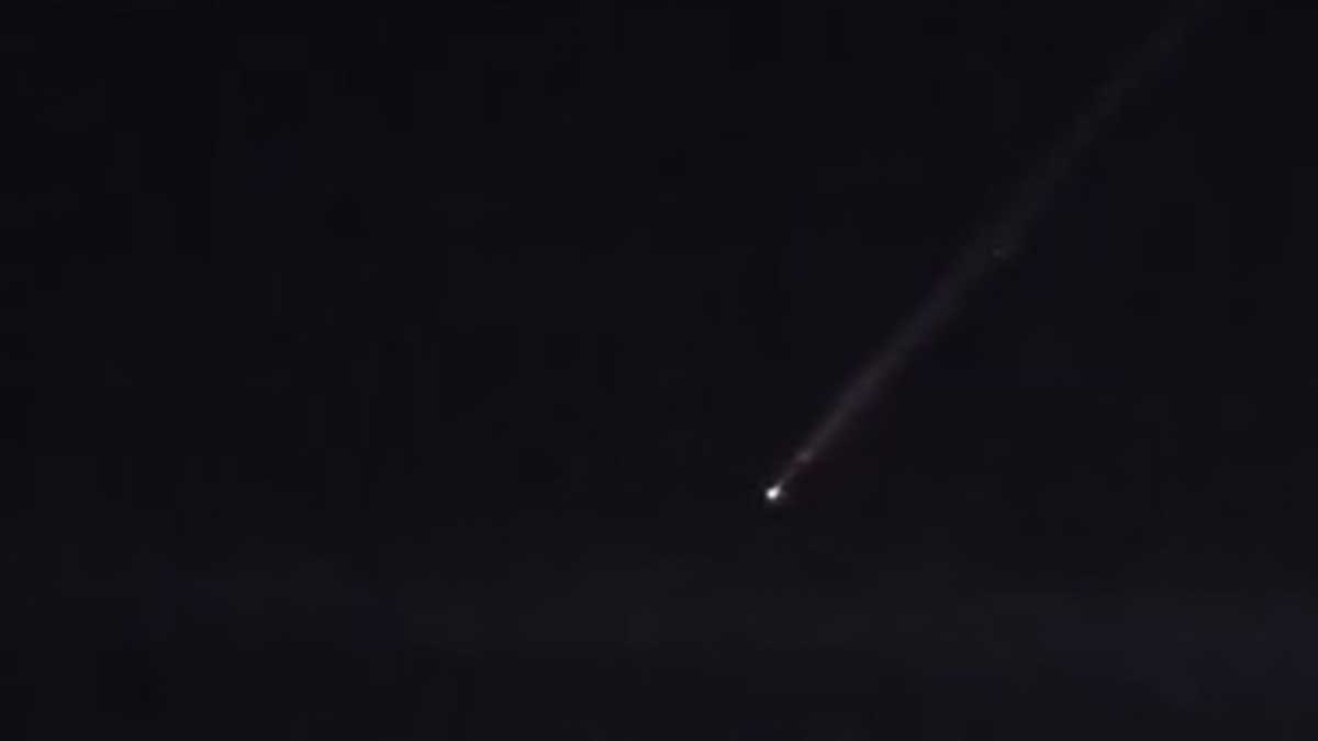 Punto de luz con estela sobre el cielo nocturno.