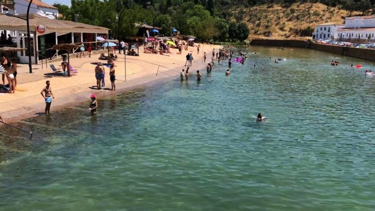 Adultos y niños bañándose en esta playa artificial en plena sierra de Sevilla.