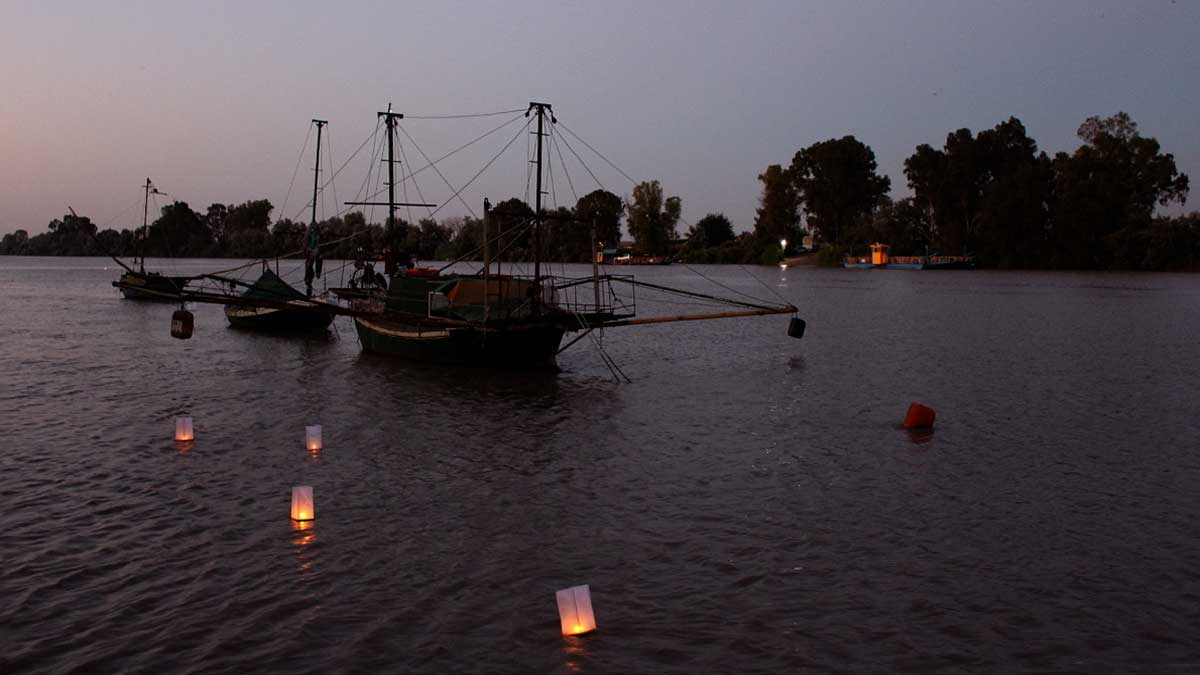 Un barco en el Guadalquivir con farolillos sobre el río.