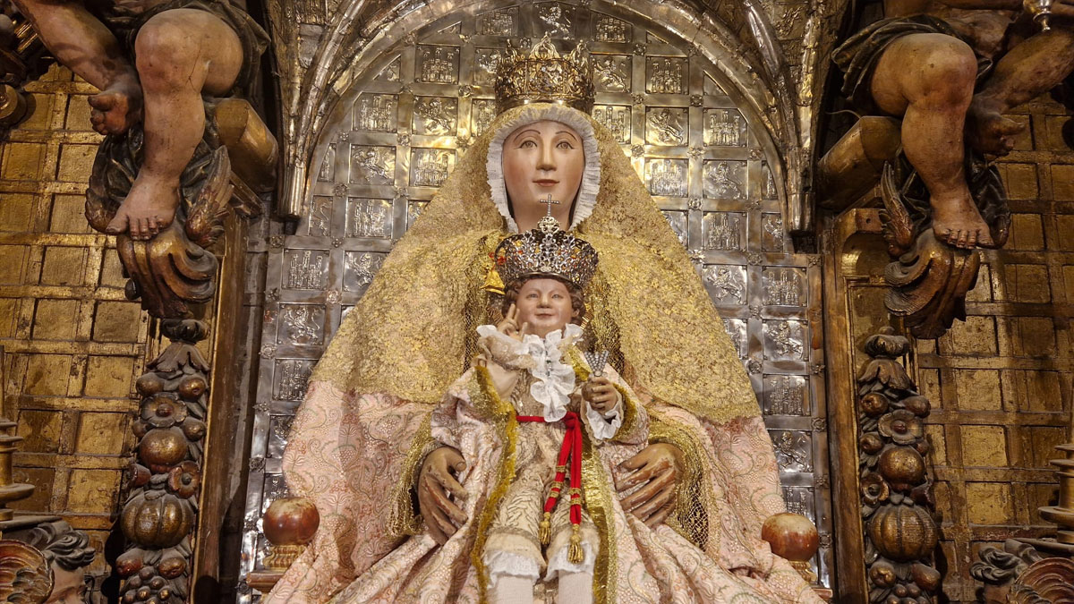 Imagen de la Virgen de los Reyes con el Niño en sus brazos, tras ella el Altar Mayor de la Catedral de Sevilla.