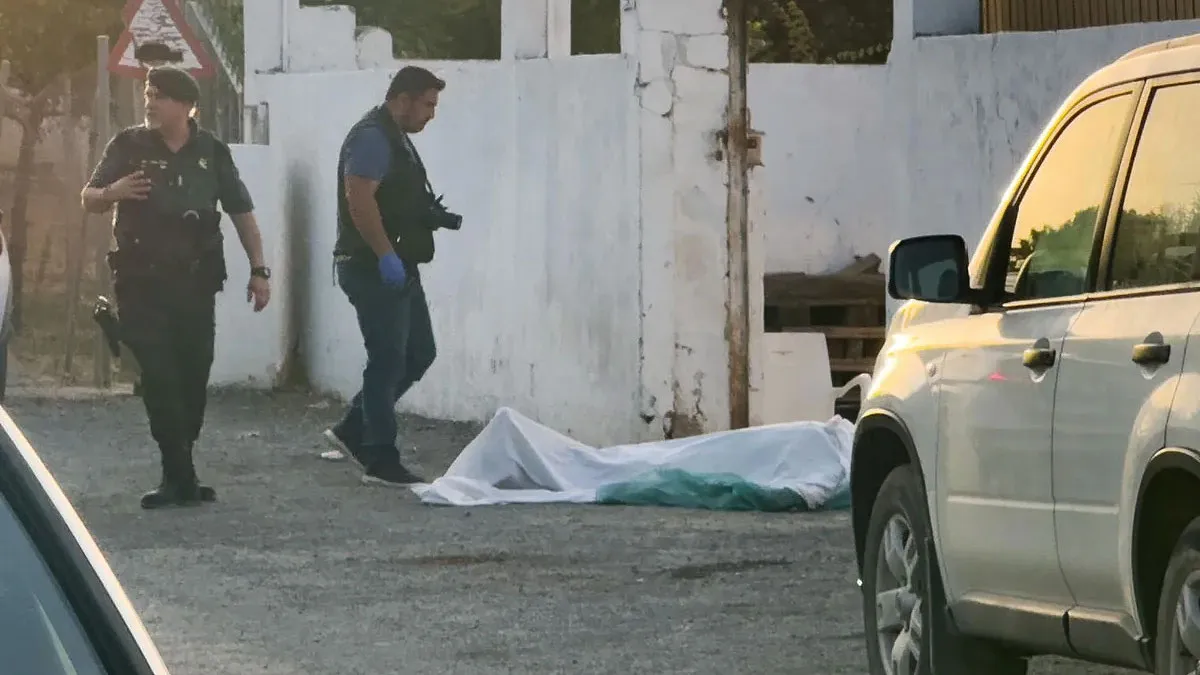 Cadáver de una de las víctimas tapado por una sábana y dos agentes de la Guardia Civil cercanos al mismo.
