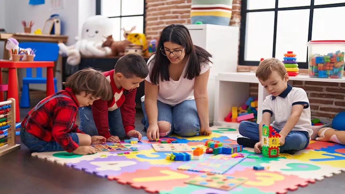 Cuidadora, niños y niñas en una guardería en el suelo jugando.