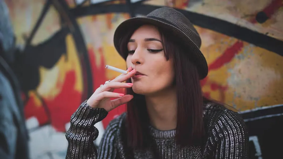 Mujer con sombrero fumando un cigarro.