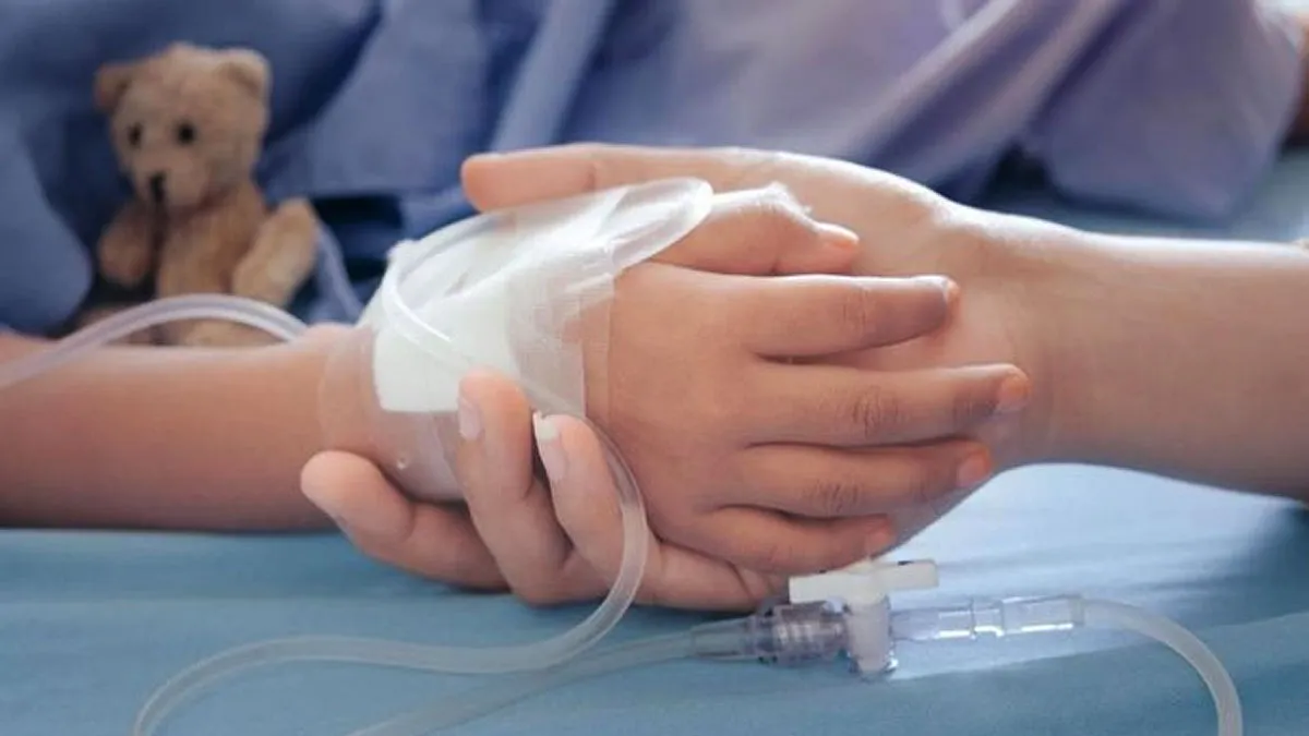 Madre da la mano a su hijo en el hospital, al fondo un osito de peluche.
