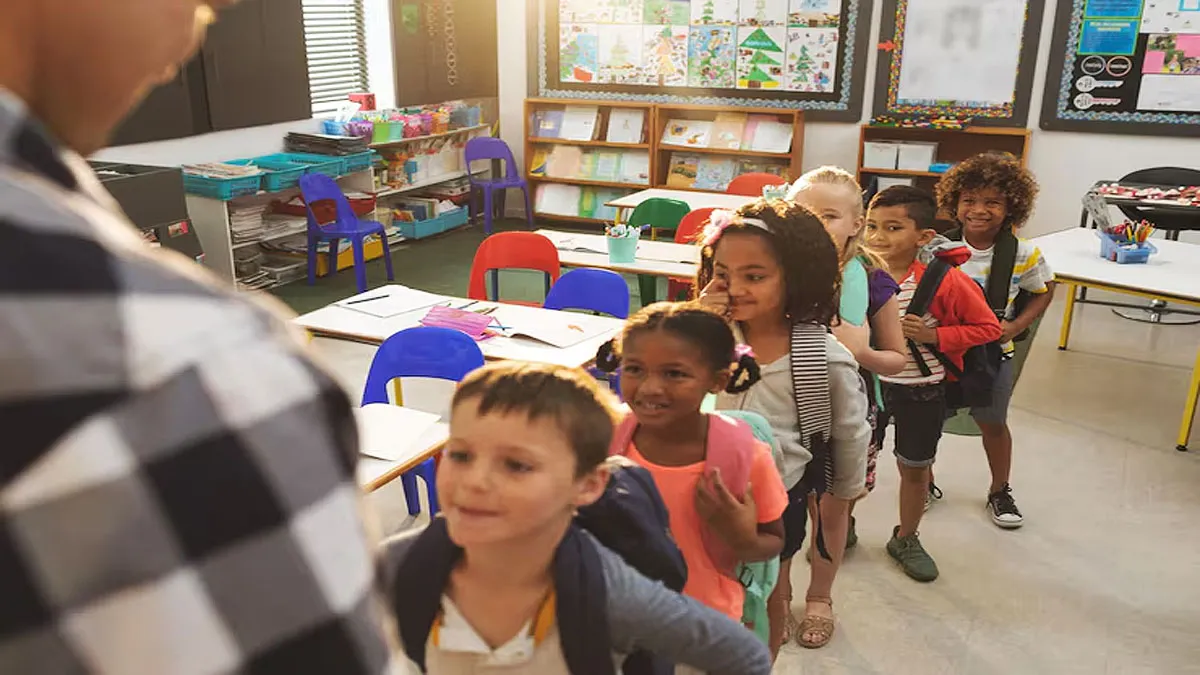 Niños haciendo una fila en el colegio ante el profesor.