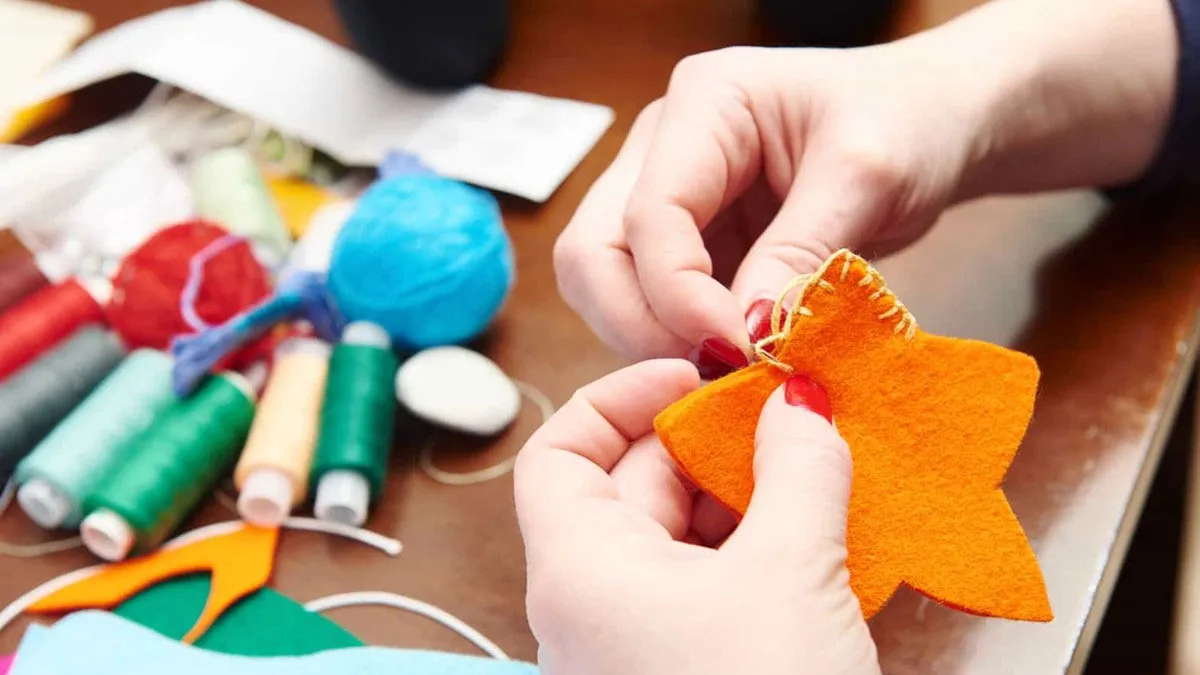 Persona cosiendo una estrella de color naranja.