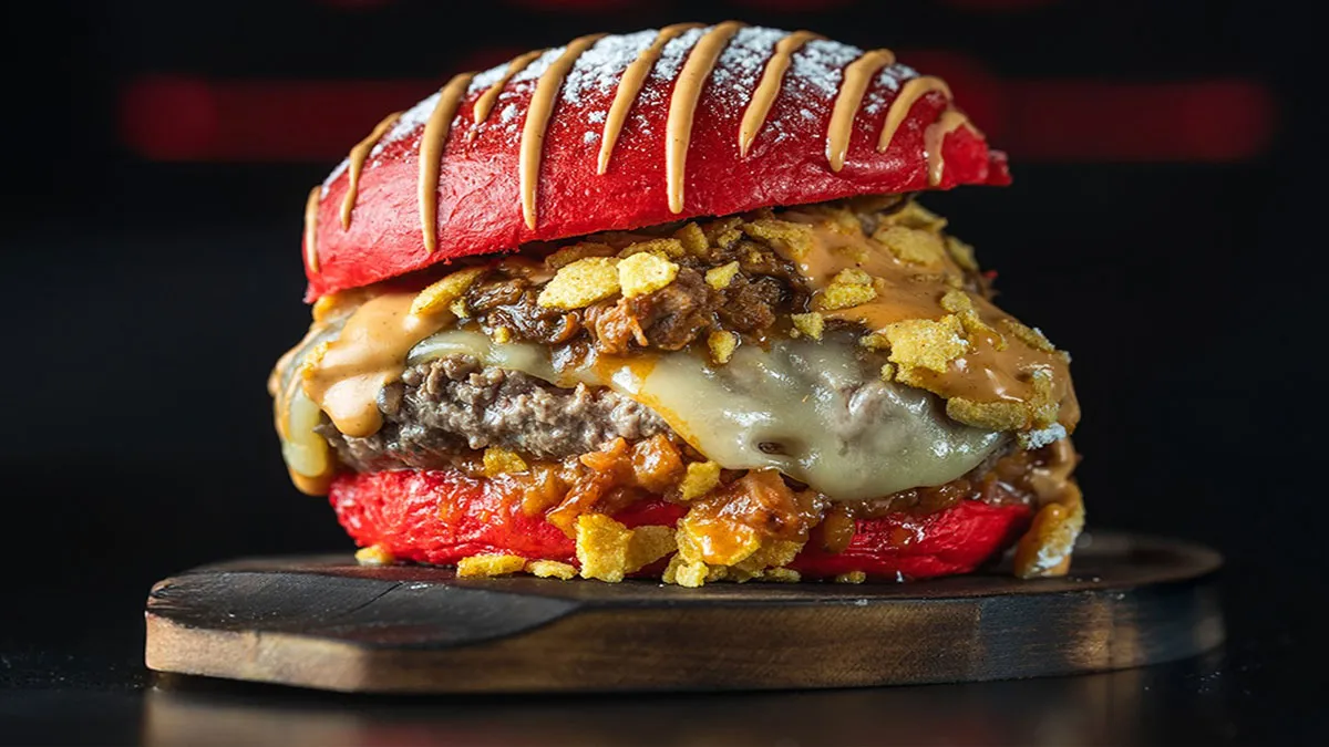 Hamburguesa jugosa y destaca el pan rojo.