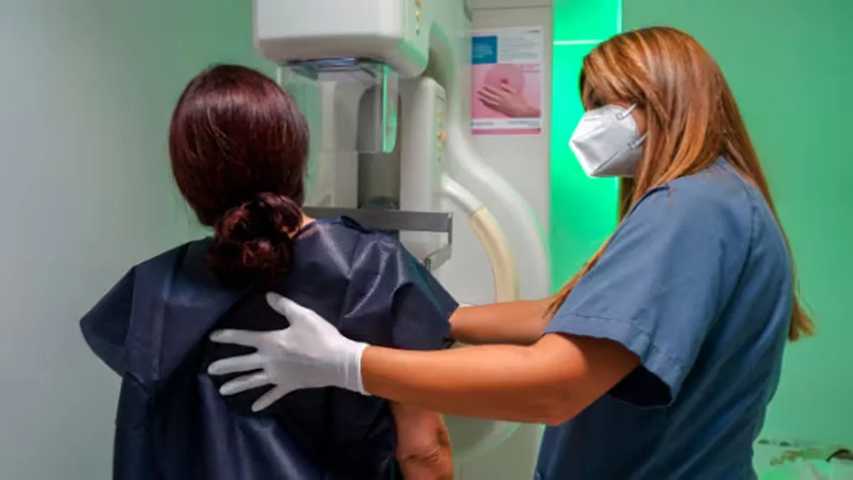 Mujer realizándose una mamografía junto a una médica.