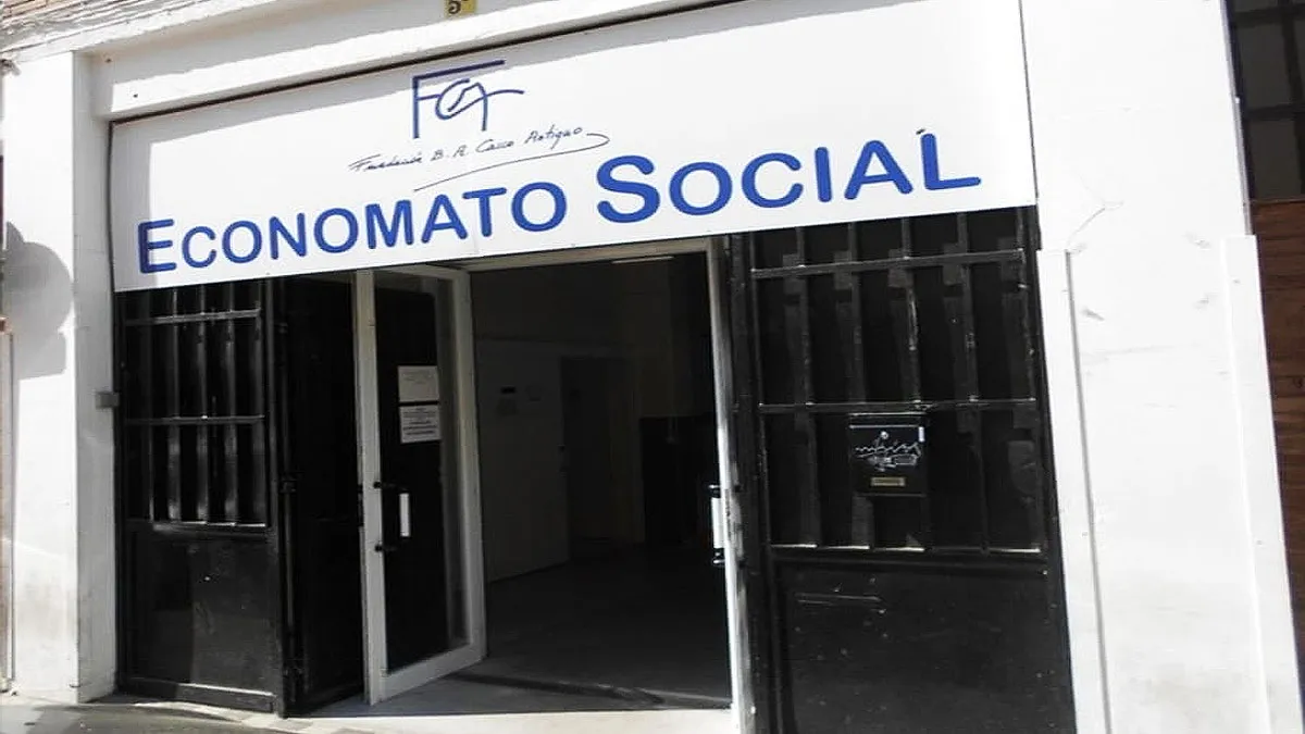 Puerta de acceso en blanca con letras azules que pone "Economato Social".