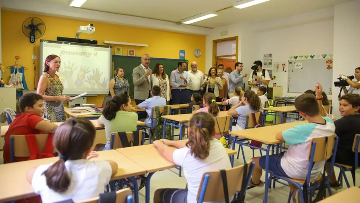 Alumnos sentados en sus pupitres atienden a una visita institucional.