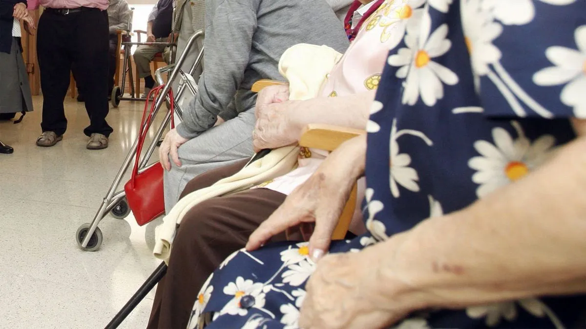 Una mujer con vestido estampado azul y flores blancas en el médico, junto a ella hay más personas.