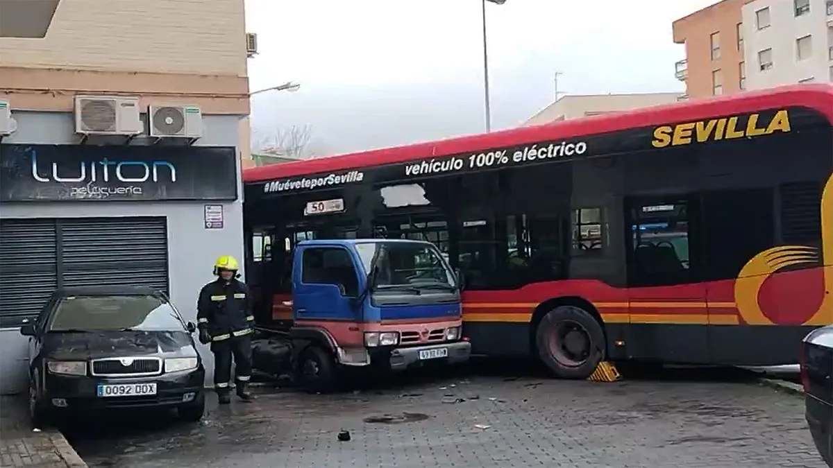 Autobús empotrado contra una pared, bombero cerca del mismo. Coches destrozados.