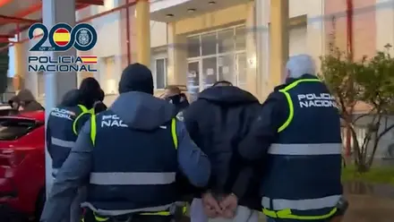 Policía con delincuente esposado entrando en comisaría.