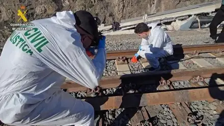 Dos agentes de la Guardia Civil, con monos blancos, fotografiando y estudiando la vía de Adamuz.