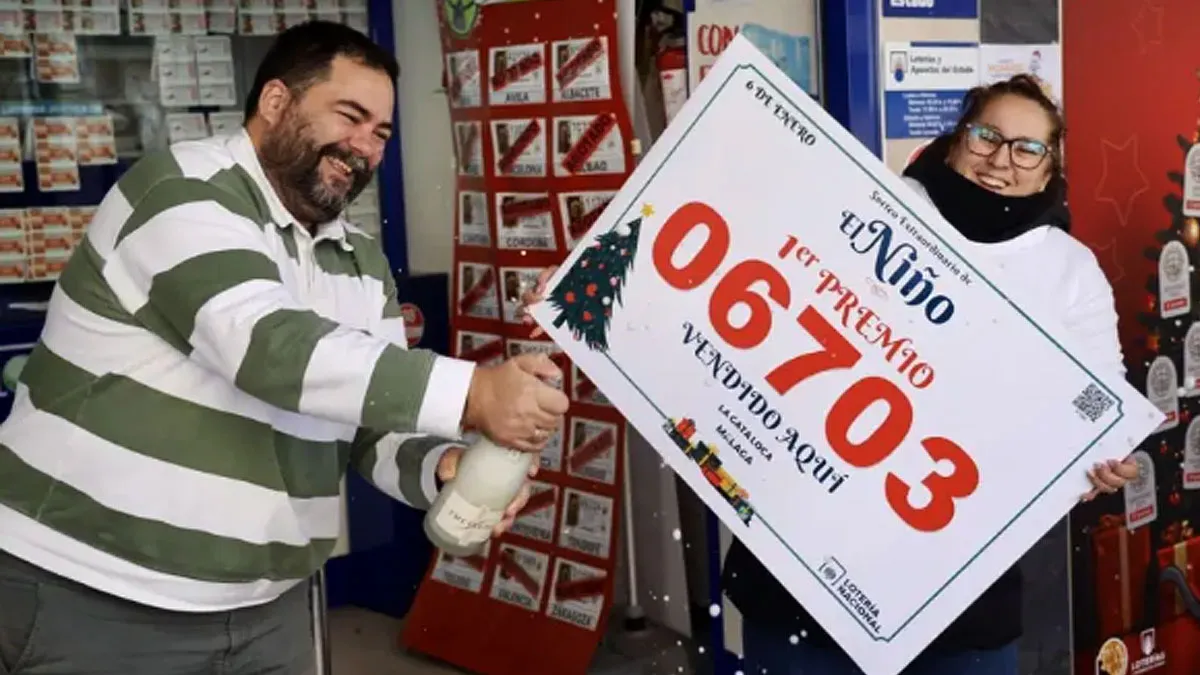 Dos personas ríen mientras una abre una botella de champán y otra sostiene el número agraciado en la Lotería.
