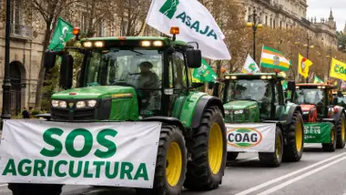 Fila de tractores verdes con pancartas reivindicativas.