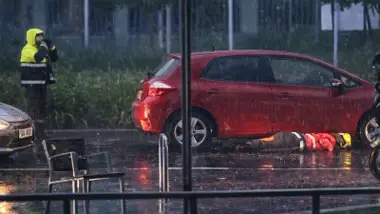 Coche rojo y un bombero mirando bajo el mismo.