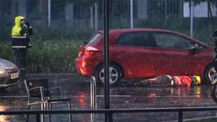 Coche rojo y un bombero mirando bajo el mismo.