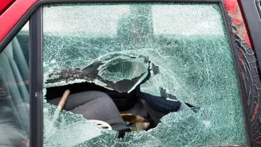 Rotura del cristal del copiloto de un coche rojo.